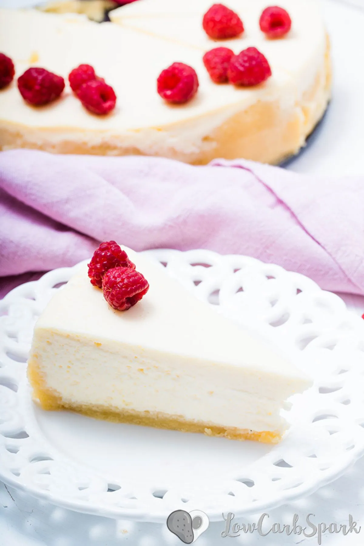 keto cheesecake slice on a plate with raspberry on top