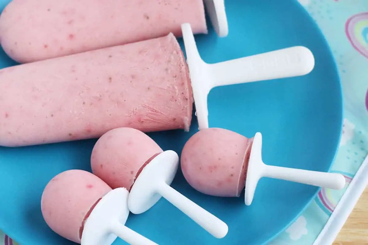 mini strawberry popsicles on blue plate